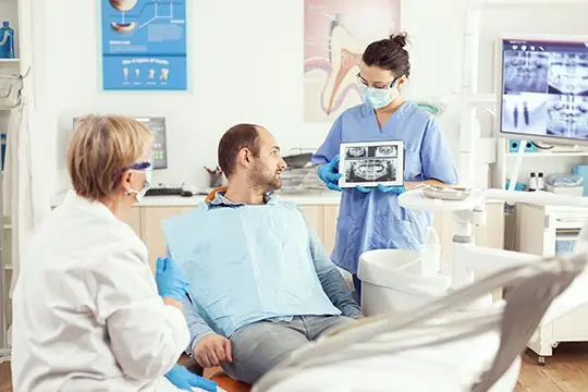 Sick man sitting on stomatological chair listening doctor procedures involving laser dentistry warrnambool